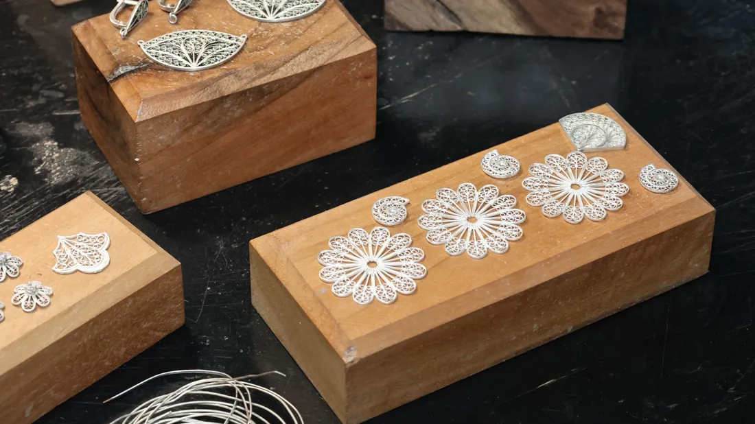 Boucles d'oreilles et bijoux en acier et argent posés sur un présentoir
