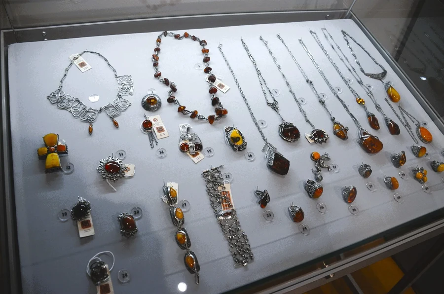 Vitrine de bijoux en ambre montés sur argent : colliers, pendentifs, bagues et broches aux teintes miel, cognac et laiteuse